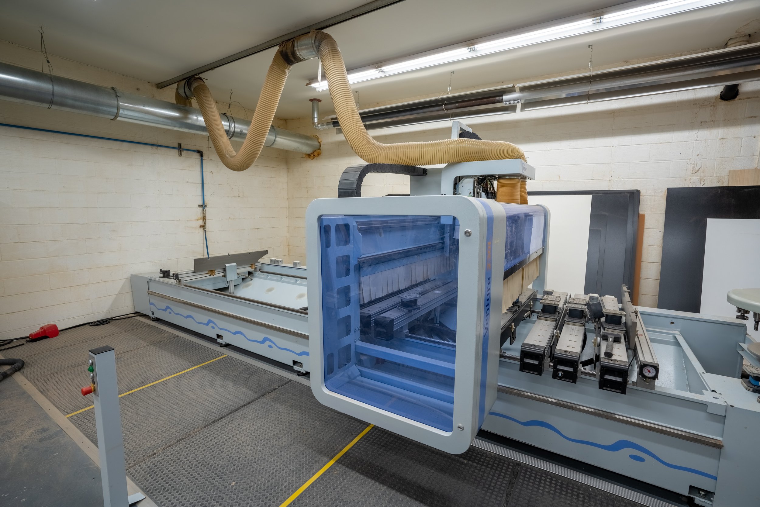 Large industrial CNC machine in a workshop with hoses and control panels.