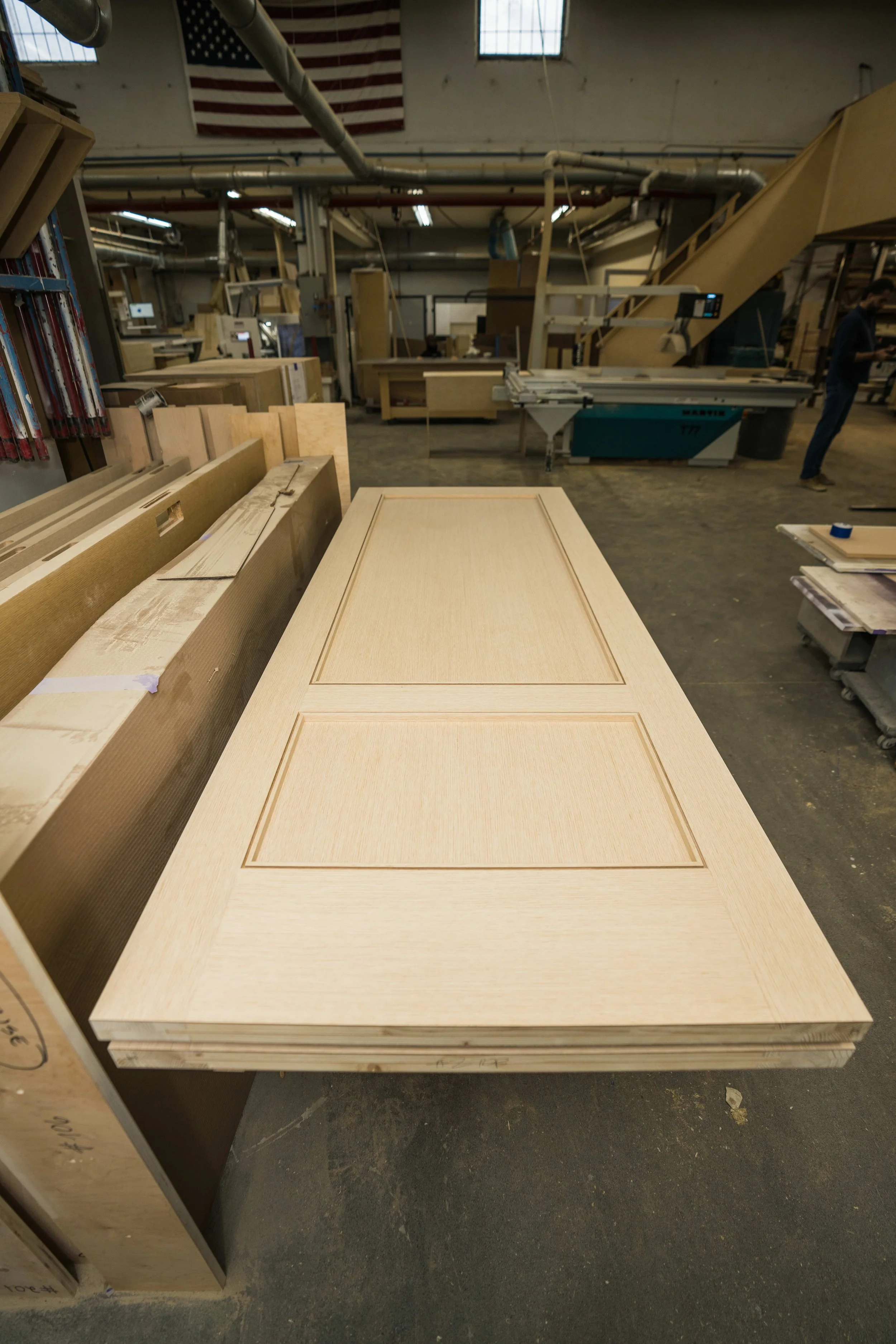 A wooden tabletop with inset panel design in a warehouse or woodworking shop.