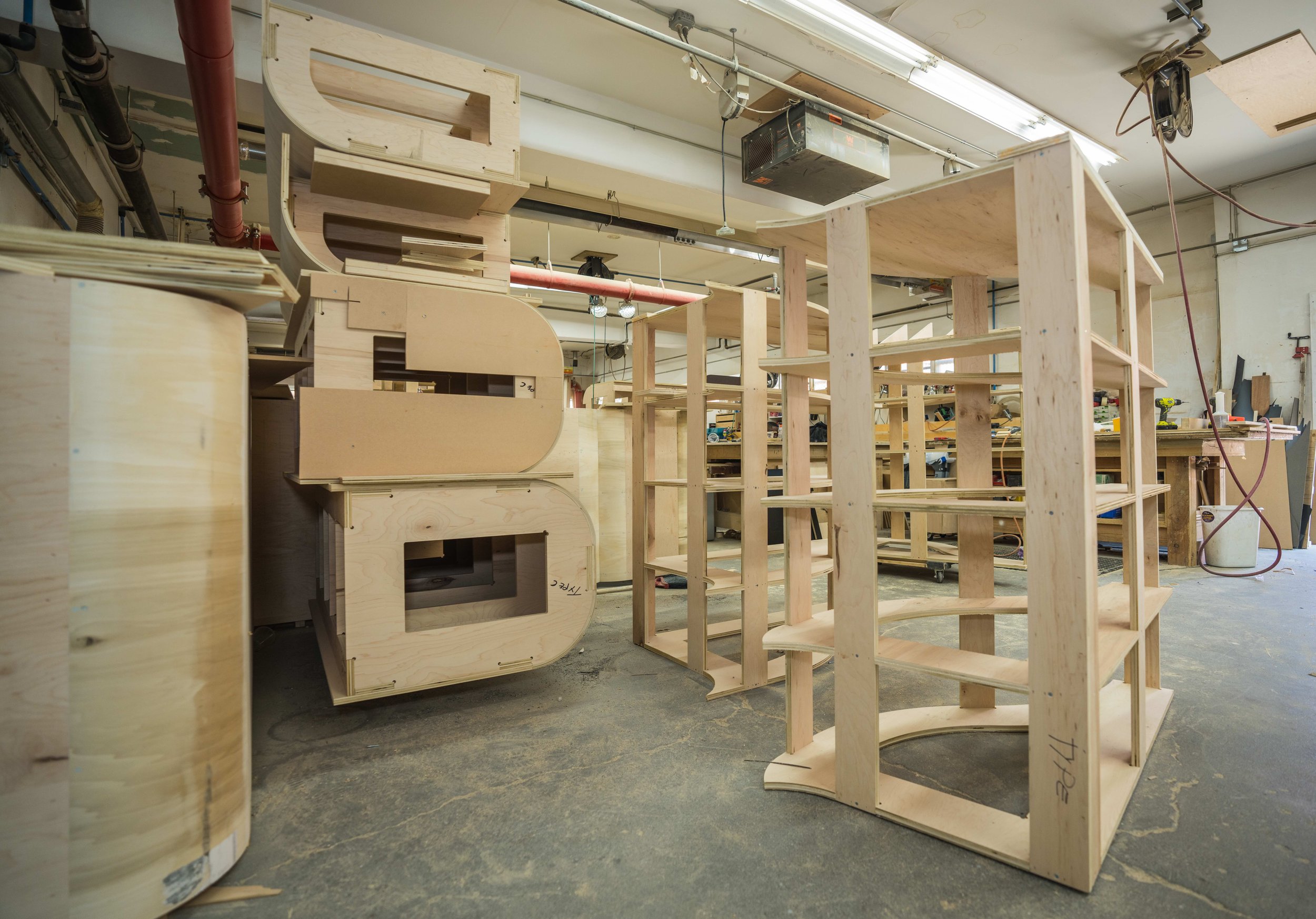 Wooden furniture pieces, frames, and shelves in a woodworking workshop.