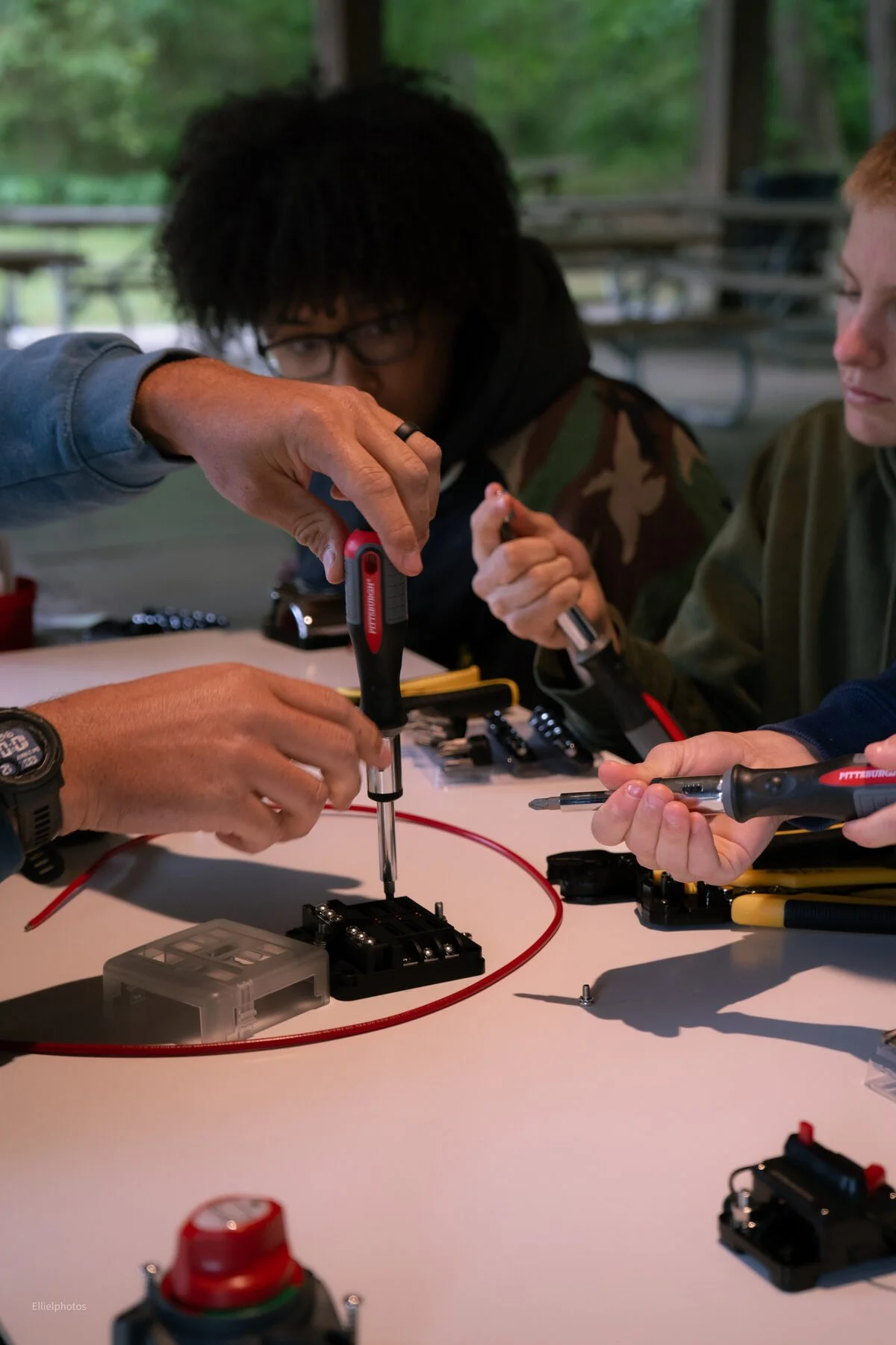 A student and volunteer wiring a fuse block at Junior Marine Tech Day
