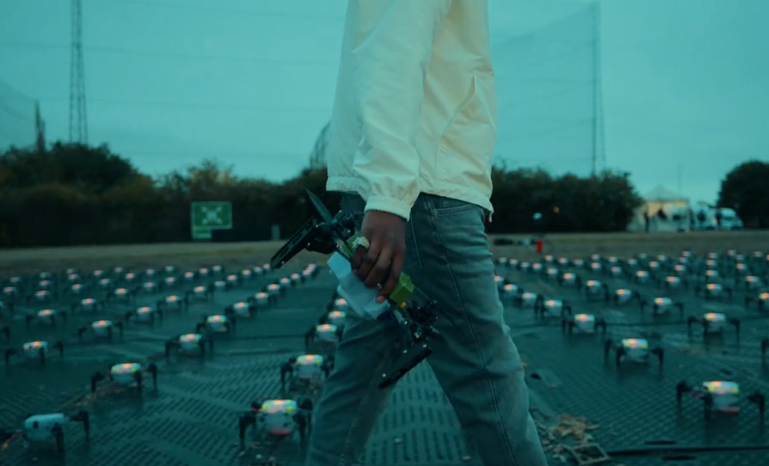 Person in white jacket holding drone on a rooftop, with an array of small security cameras installed on the surface.