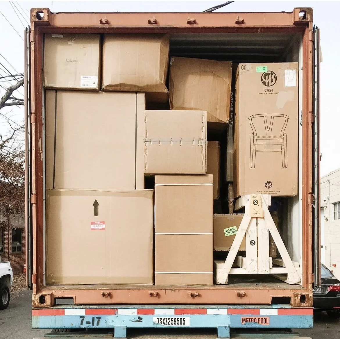 The inside of a shipping container filled with various cardboard boxes and packaging, including a box with a chair illustration.