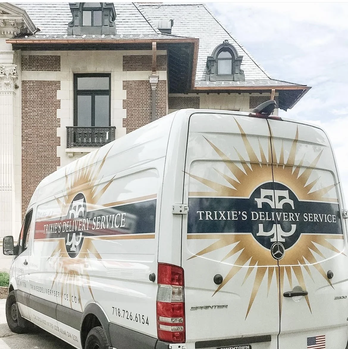A delivery van with the logo and name "Trixie's Delivery Service" parked in front of a large brick house with dormer windows.