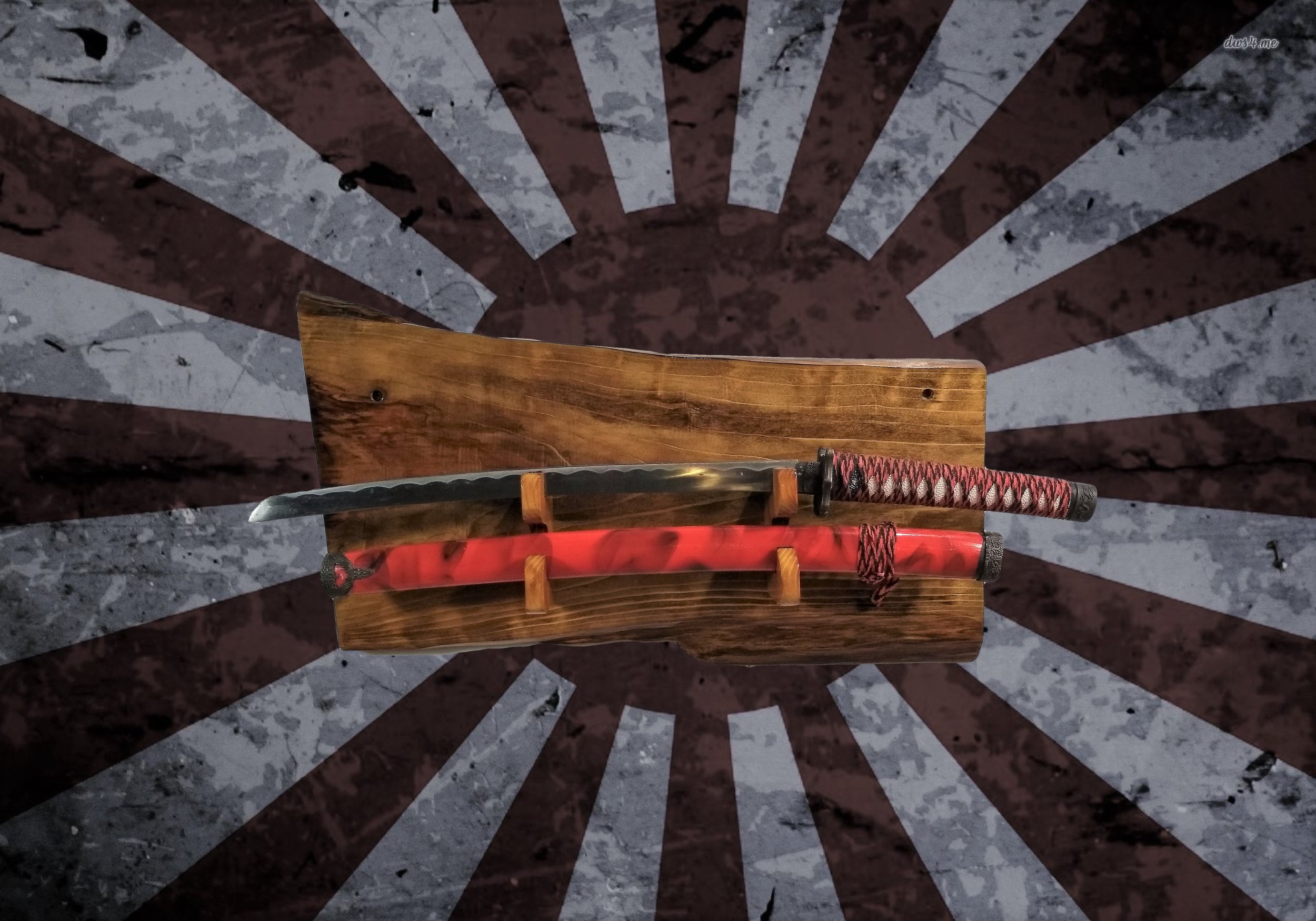 A wooden display stand holding a tanto-style knife with a black and red wrapped handle and a red sheath, set against a grunge wall with a sunburst pattern radiating from behind.
