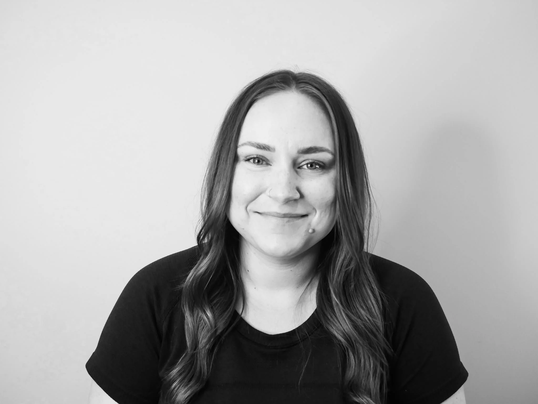A young woman smiling confidently against a plain light background.