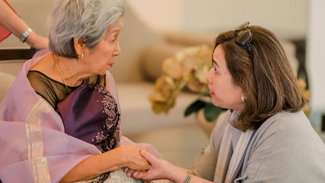 Woman caring for her elderly mother, holding her hand and talking to her about creating an estate plan.