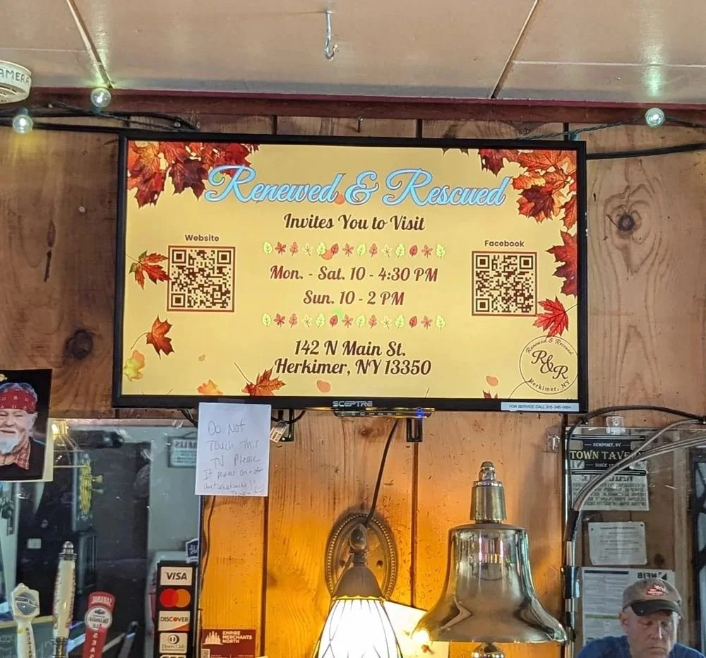 ProBoard screen inside a local business displaying an autumn-themed ad with a QR code, surrounded by wall decor