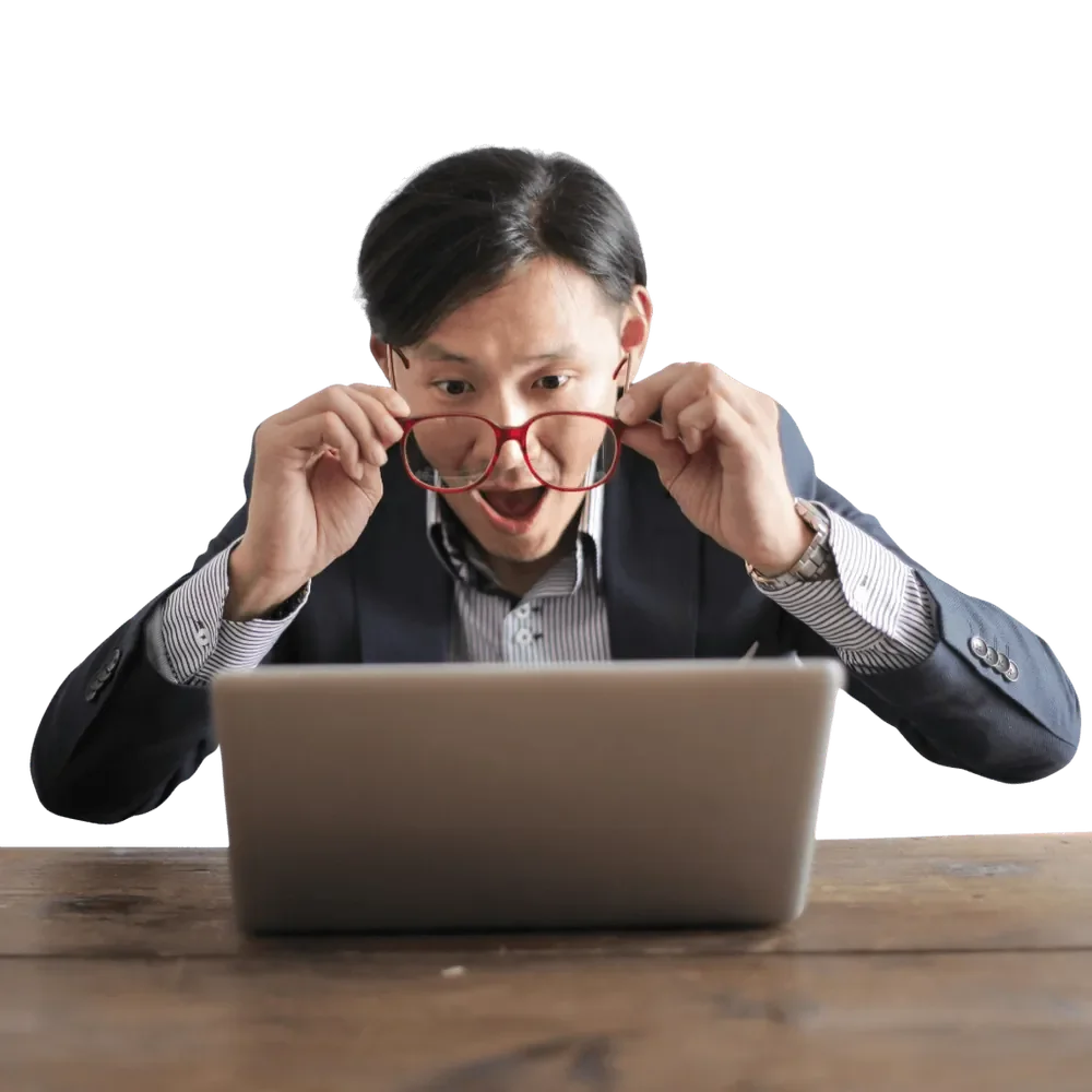 Surprised man in a suit and glasses looking at a laptop screen