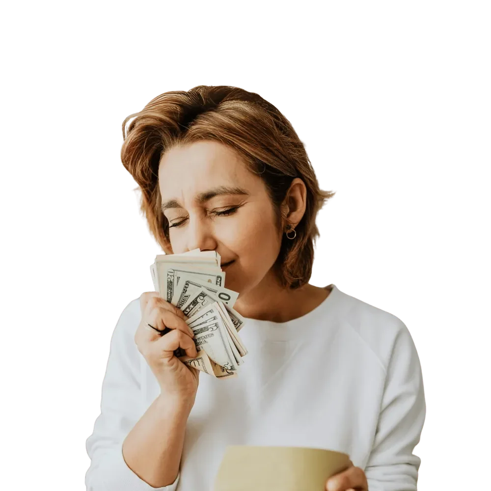 Smiling woman in a white sweater fanning a handful of cash under her nose