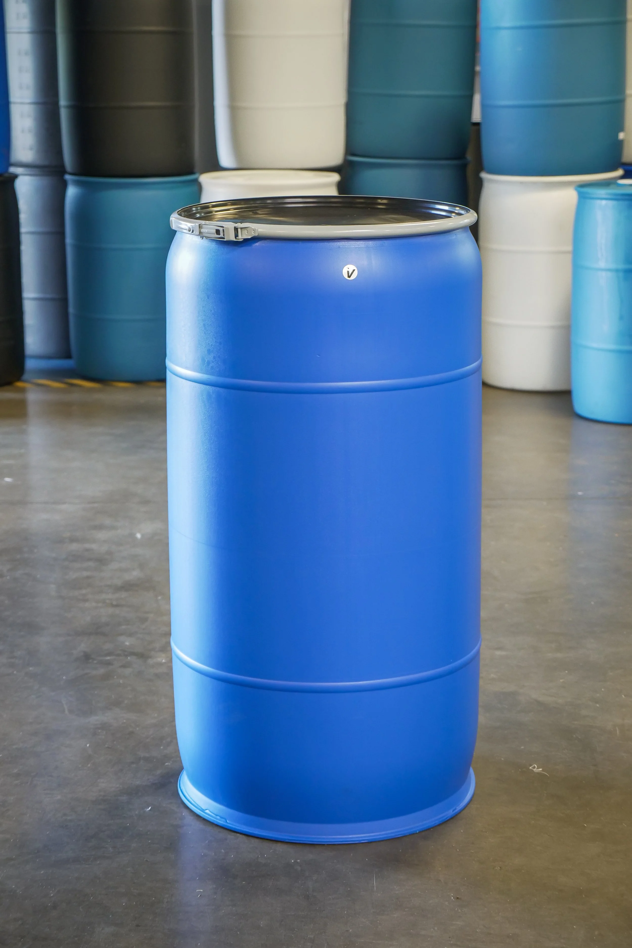 Blue plastic barrel in front of stacked other barrels in various colors