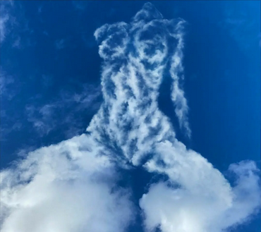 womans body outlined in white puffy sky against a bright blue background