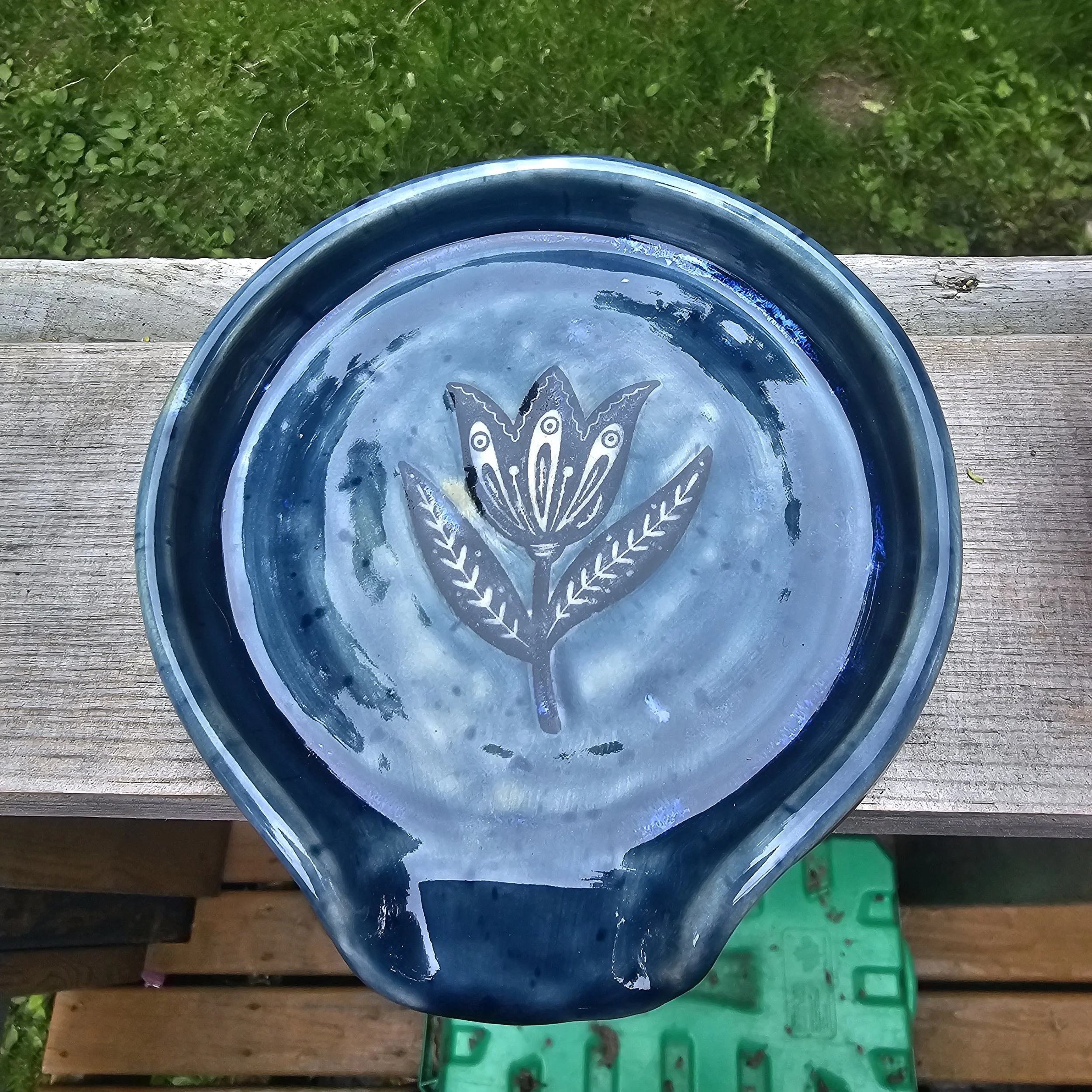 Spoon rest, blue, with flower in the middle.