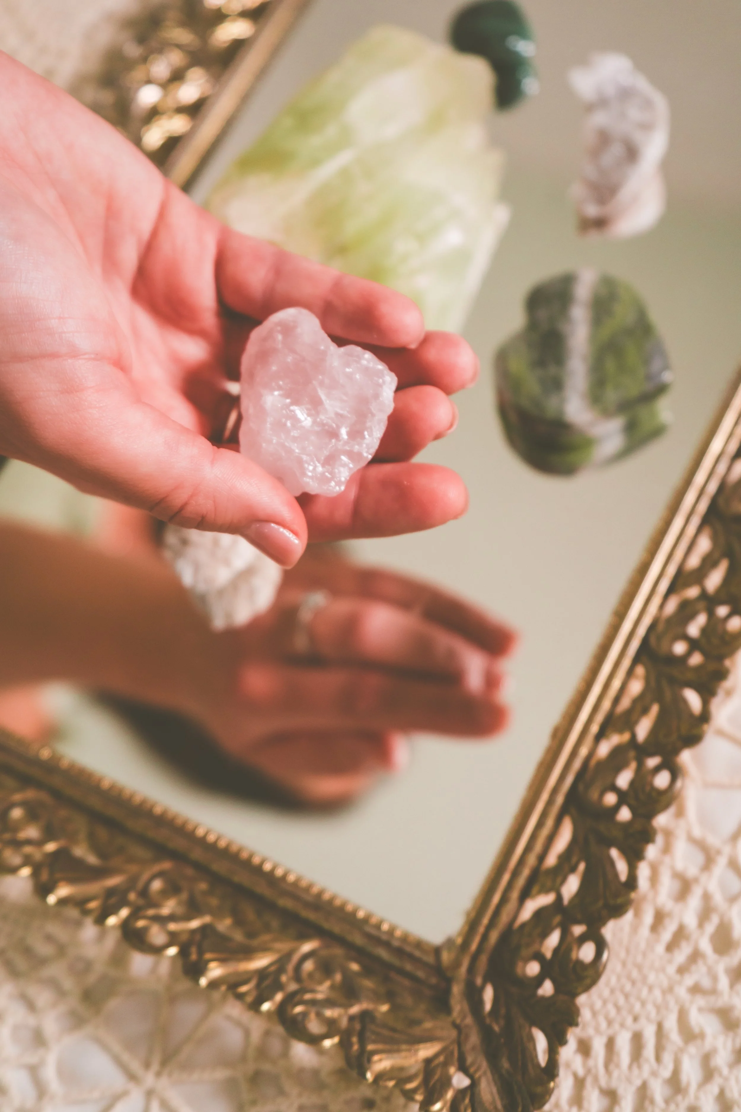 Grounding crystal used to support relaxation and nervous system healing at Greenlight Healing. Hand holding a crystal in a mirrored image. Gold frame.