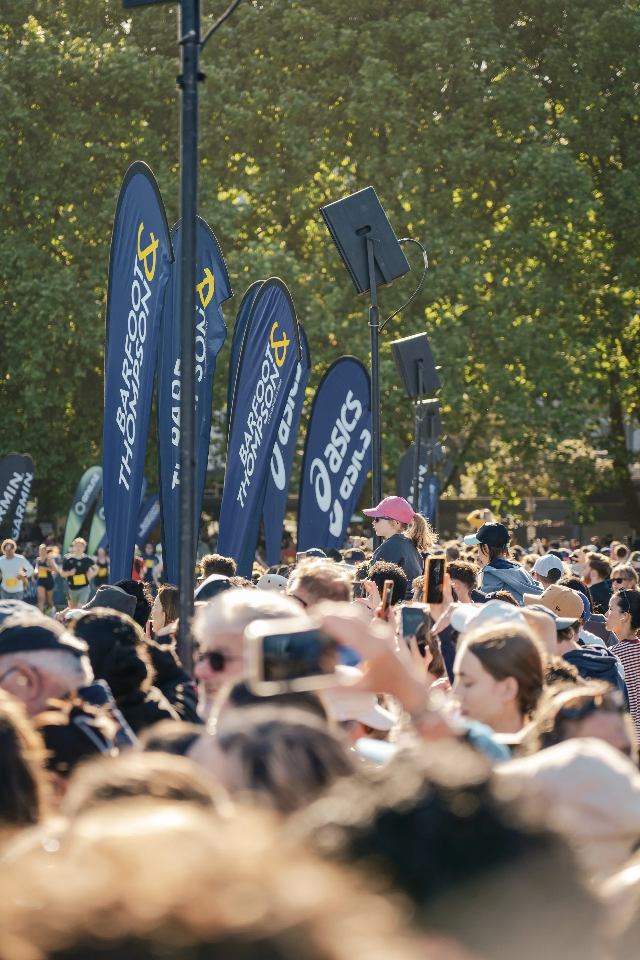 Crowd of people at an outdoor event with tall blue banners that read 'Garmin Forerunner' and 'Sport'.