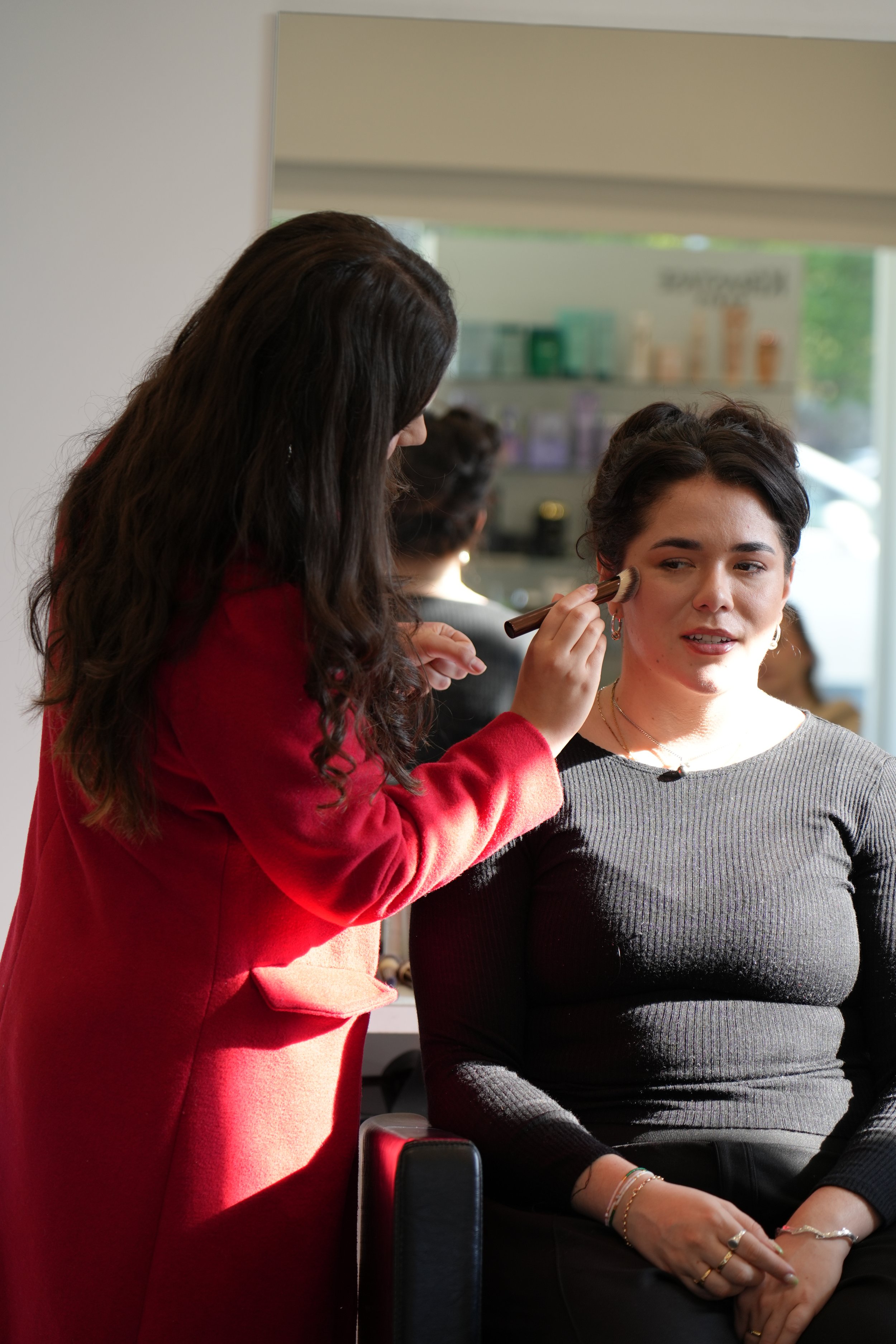 Makeup artist applying makeup to a woman in a salon or studio.