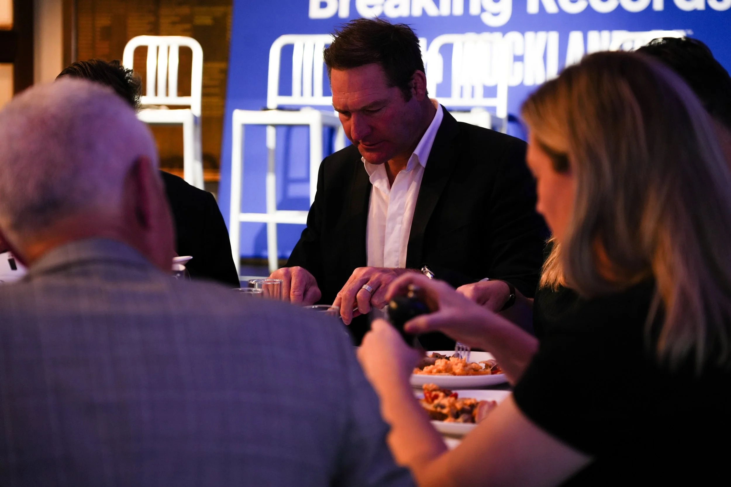 People dining at a restaurant with a blue screen in the background displaying the words 'Breaking Records' in white text.