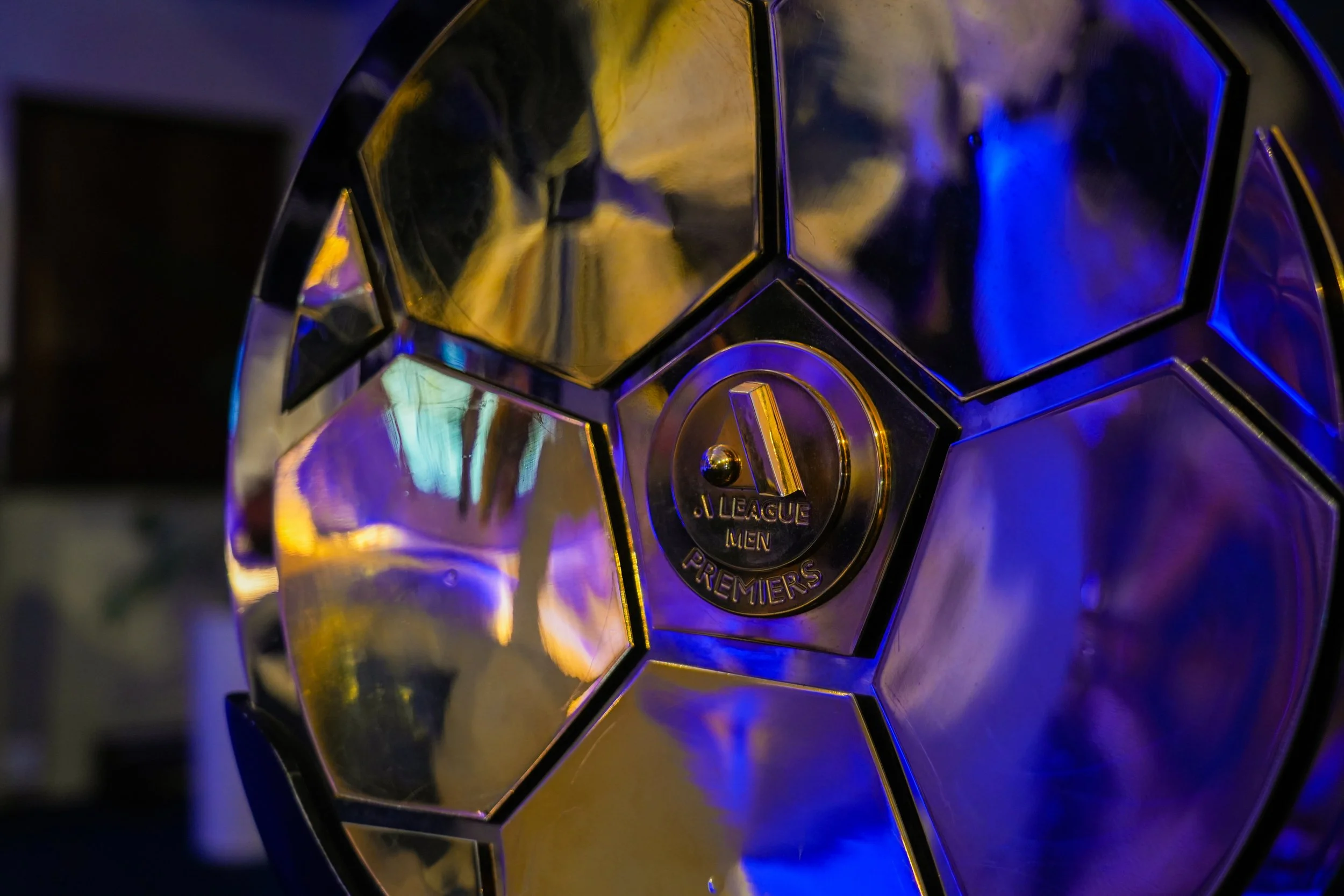 A shiny, reflective soccer ball with a badge in the center that reads 'Premier League' and 'Men'.