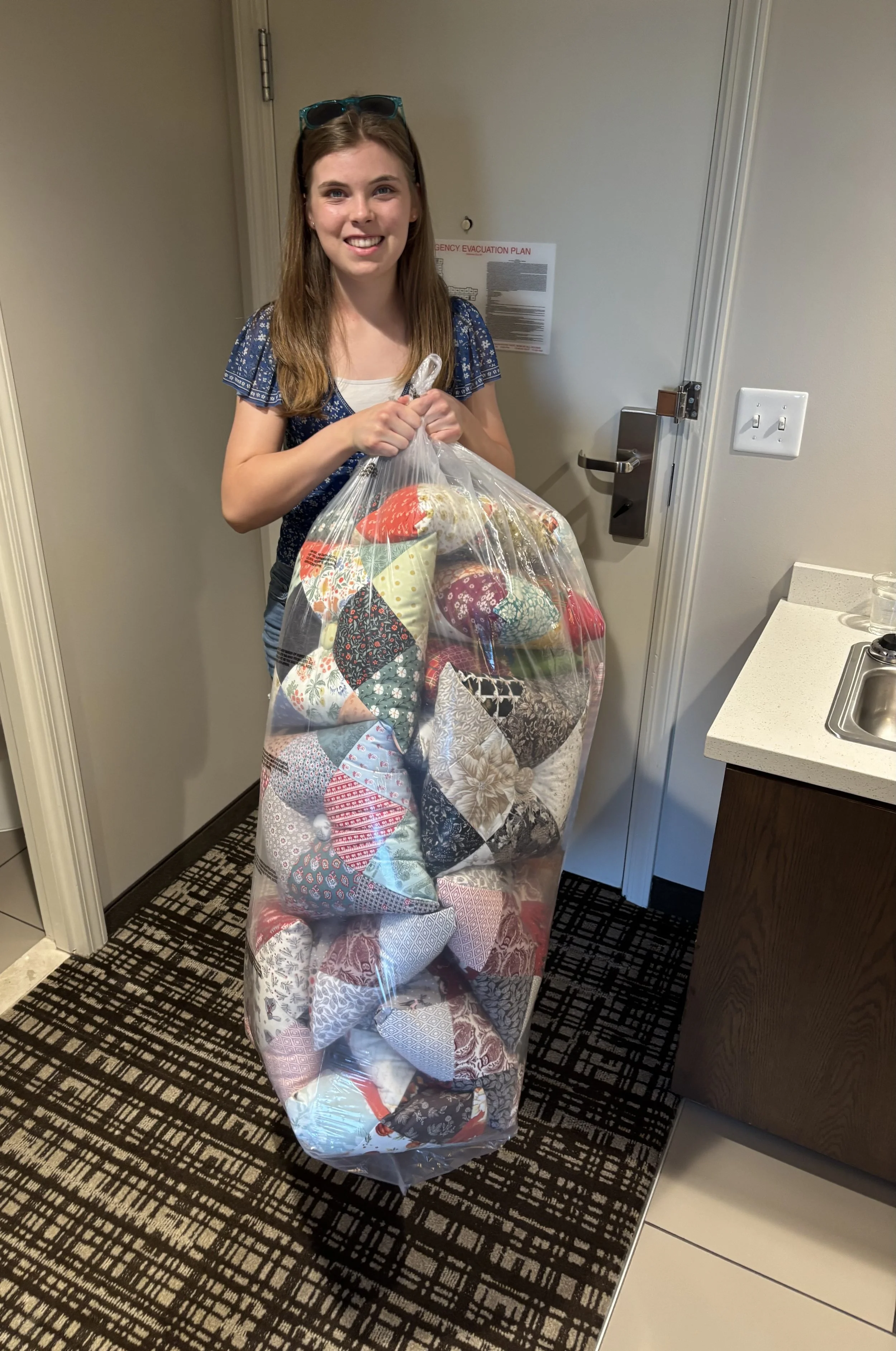Brianna Clark holding a large bag full of pillows she made.