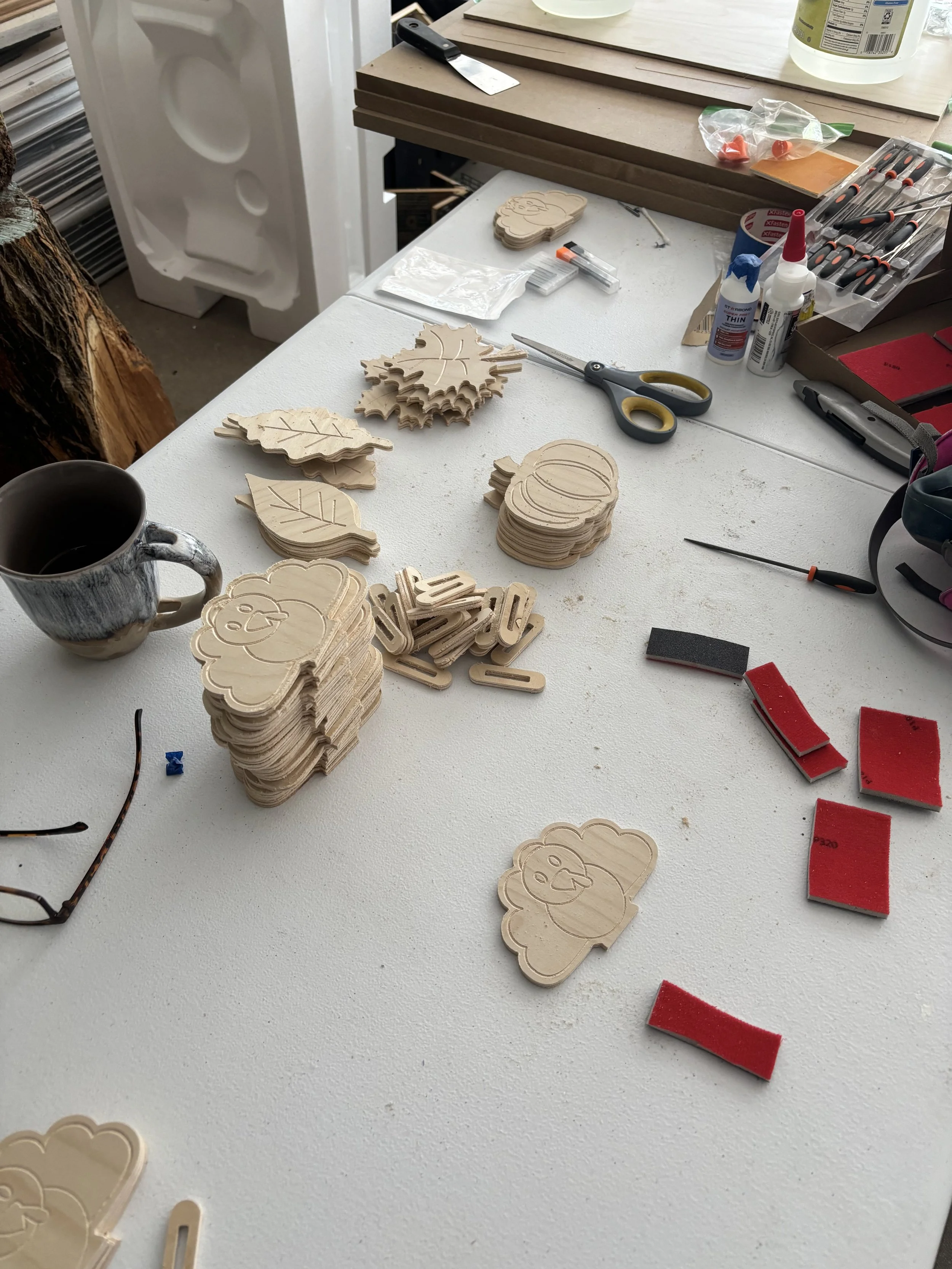 Wood cutouts in the shape of turkeys, leaves, and pumpkins, spread out on a table.