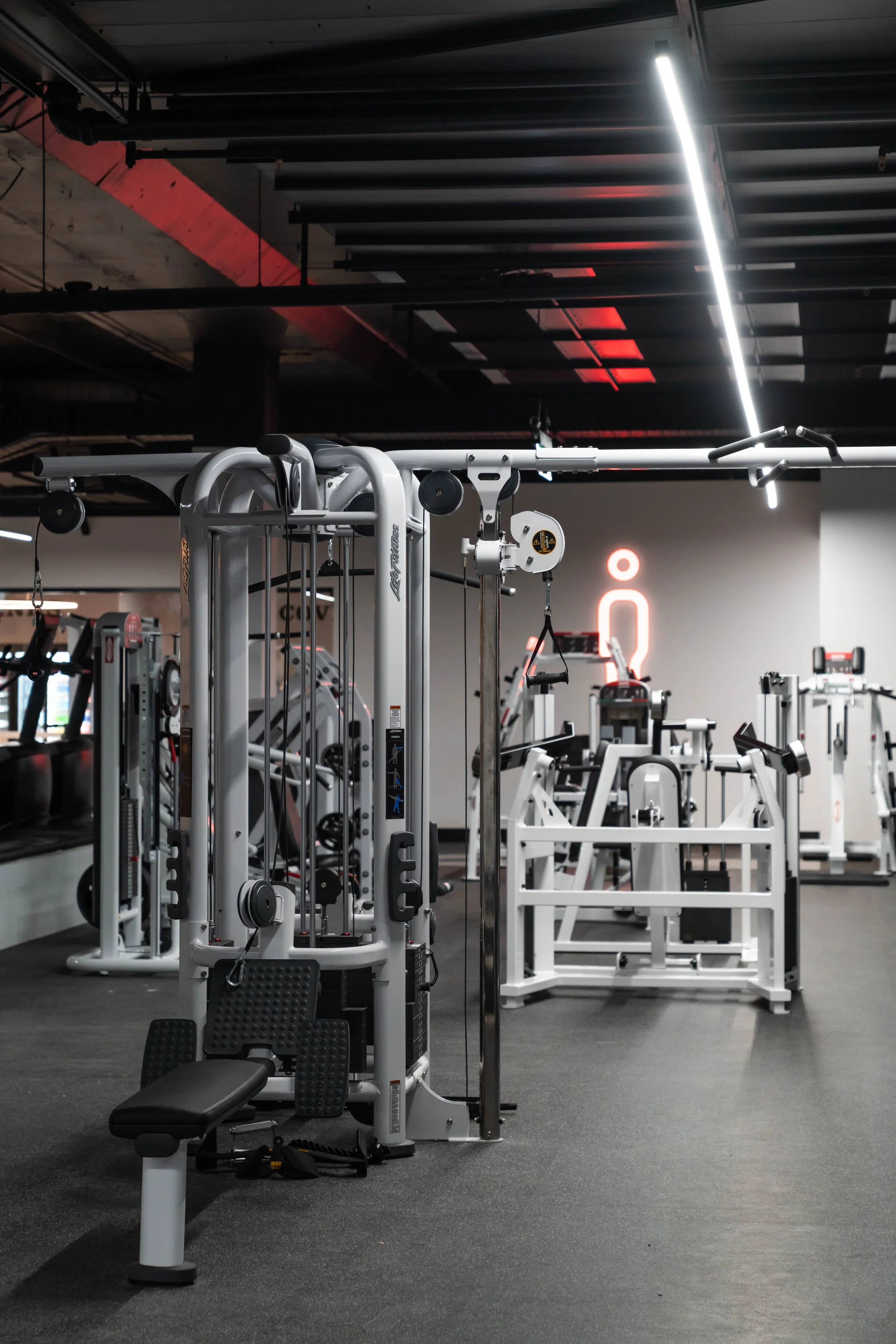 gym with various strength training equipment and a neon sign in the background.