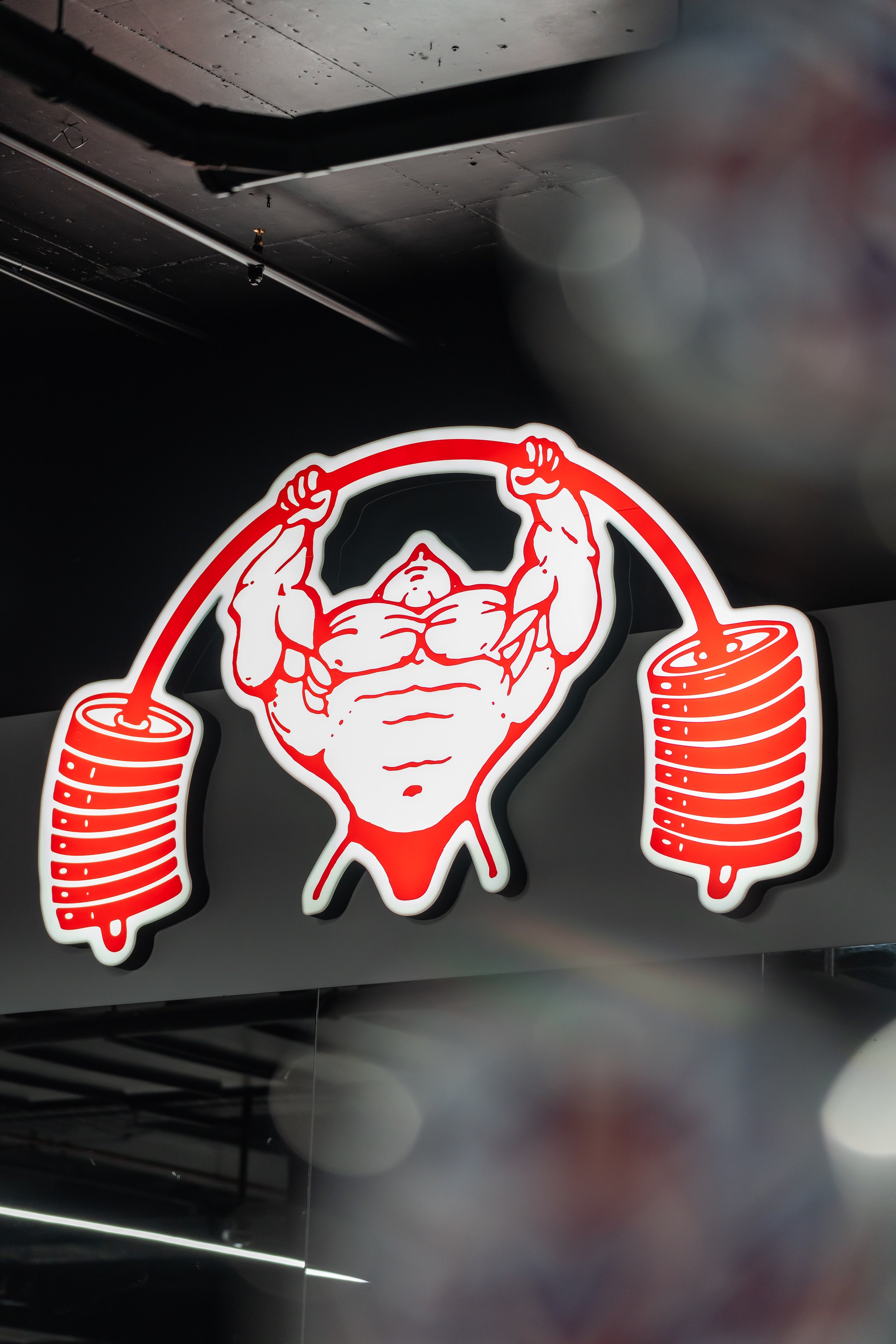 A neon sign featuring a muscular man lifting a barbell with weights that resemble rolled pancakes.