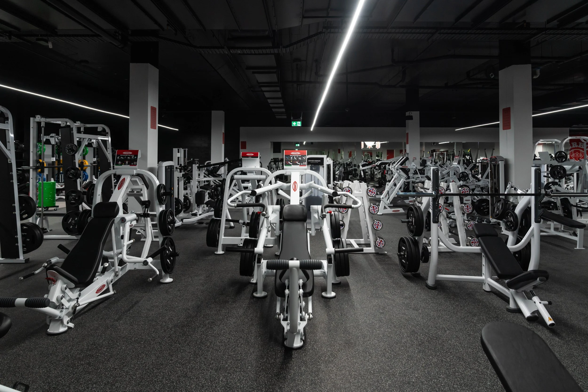 gym with weightlifting equipment, benches, and exercise machines in a spacious, well-lit room.