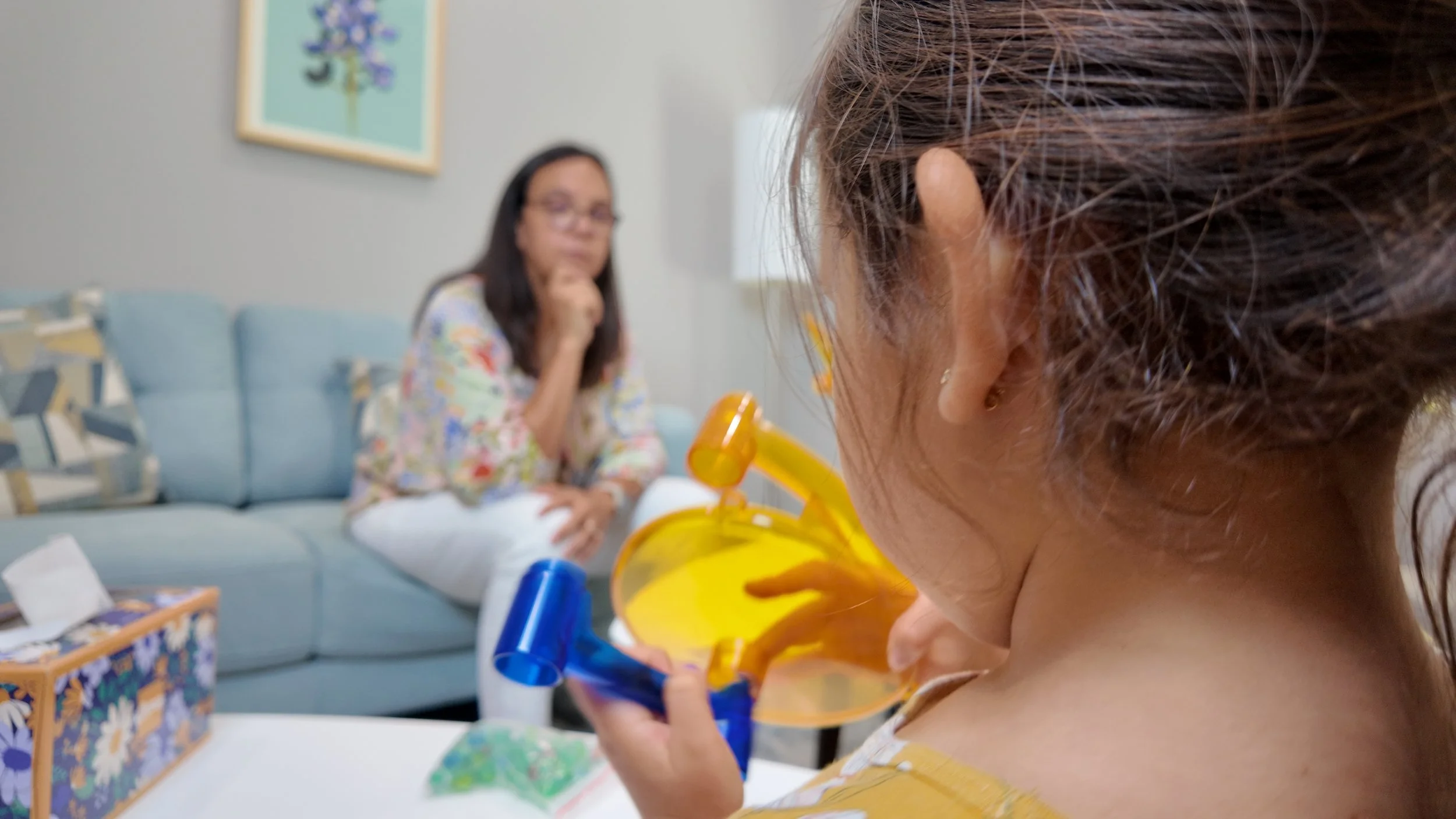 Child in foreground and therapist in background at a play therapy session