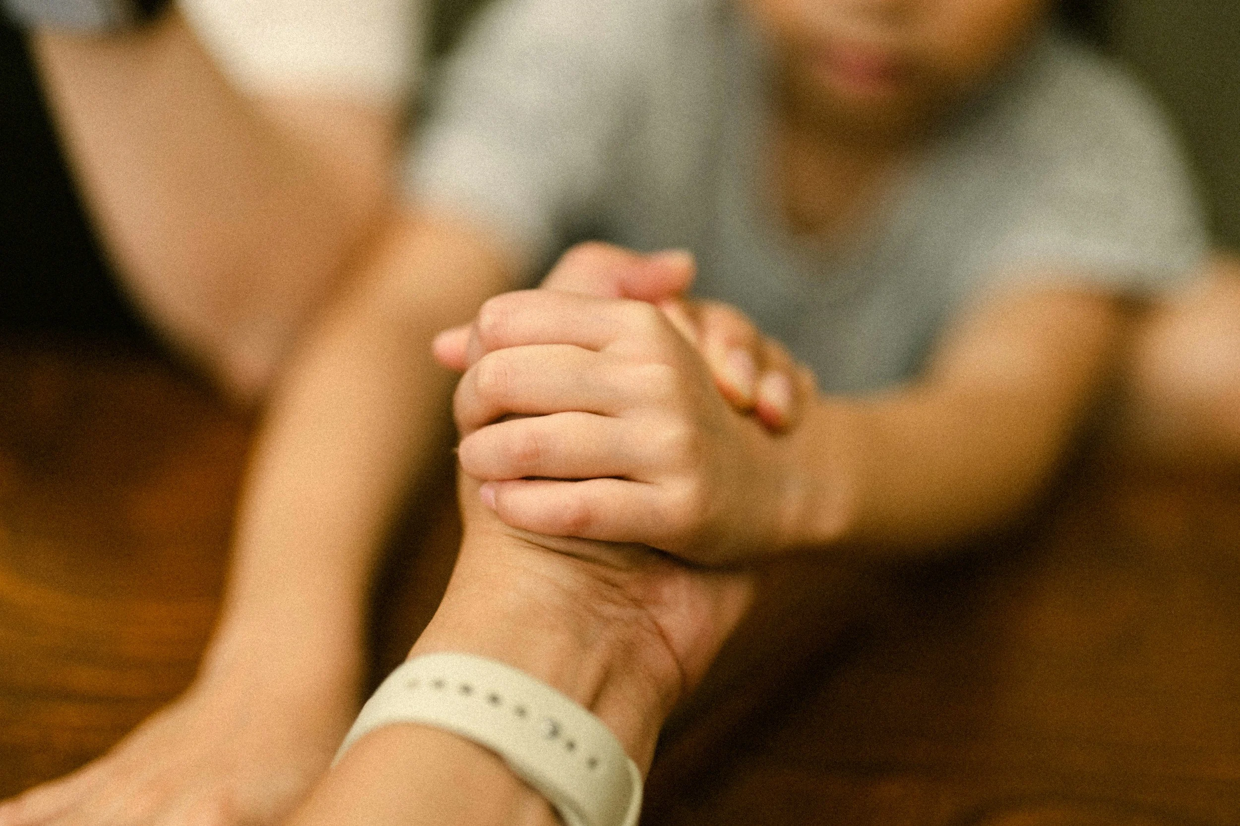 An image of a parent and child's hands clasping each other.