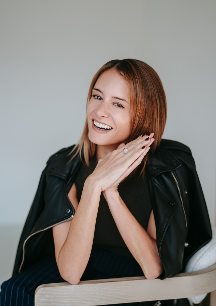 brunette lady with elbows rested on table, smiling to camera