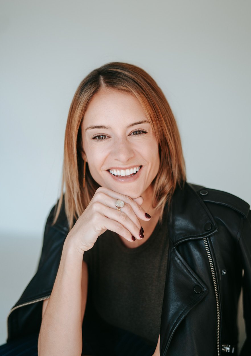 brunette coach smiling to camera wearing a leather jacket