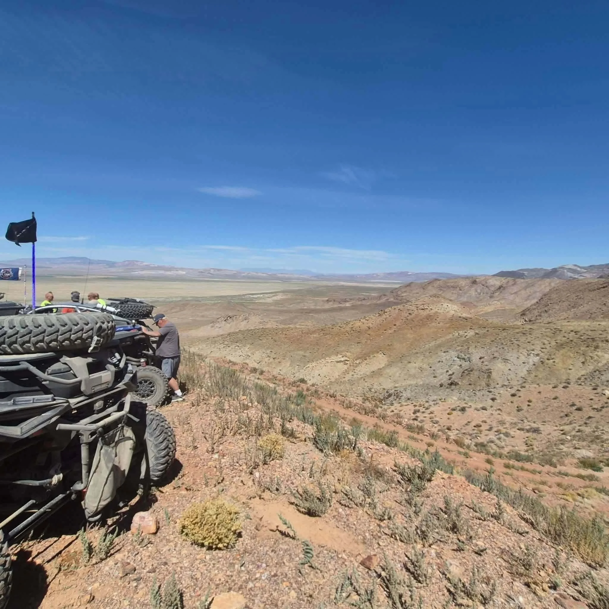 Rider performing trailside maintenance on an off-road vehicle with a sweeping desert valley view during the 2026 Dyer - Fish Lake Poker Run