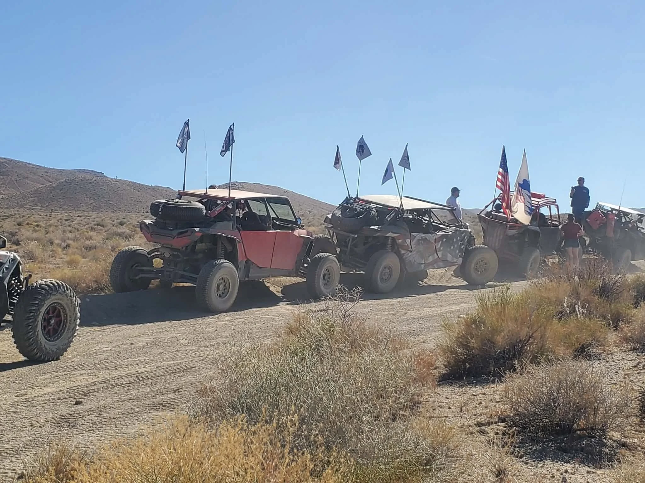 Convoy of flagged off-road UTVs traveling the desert trail during the 2026 Dyer - Fish Lake Poker Run