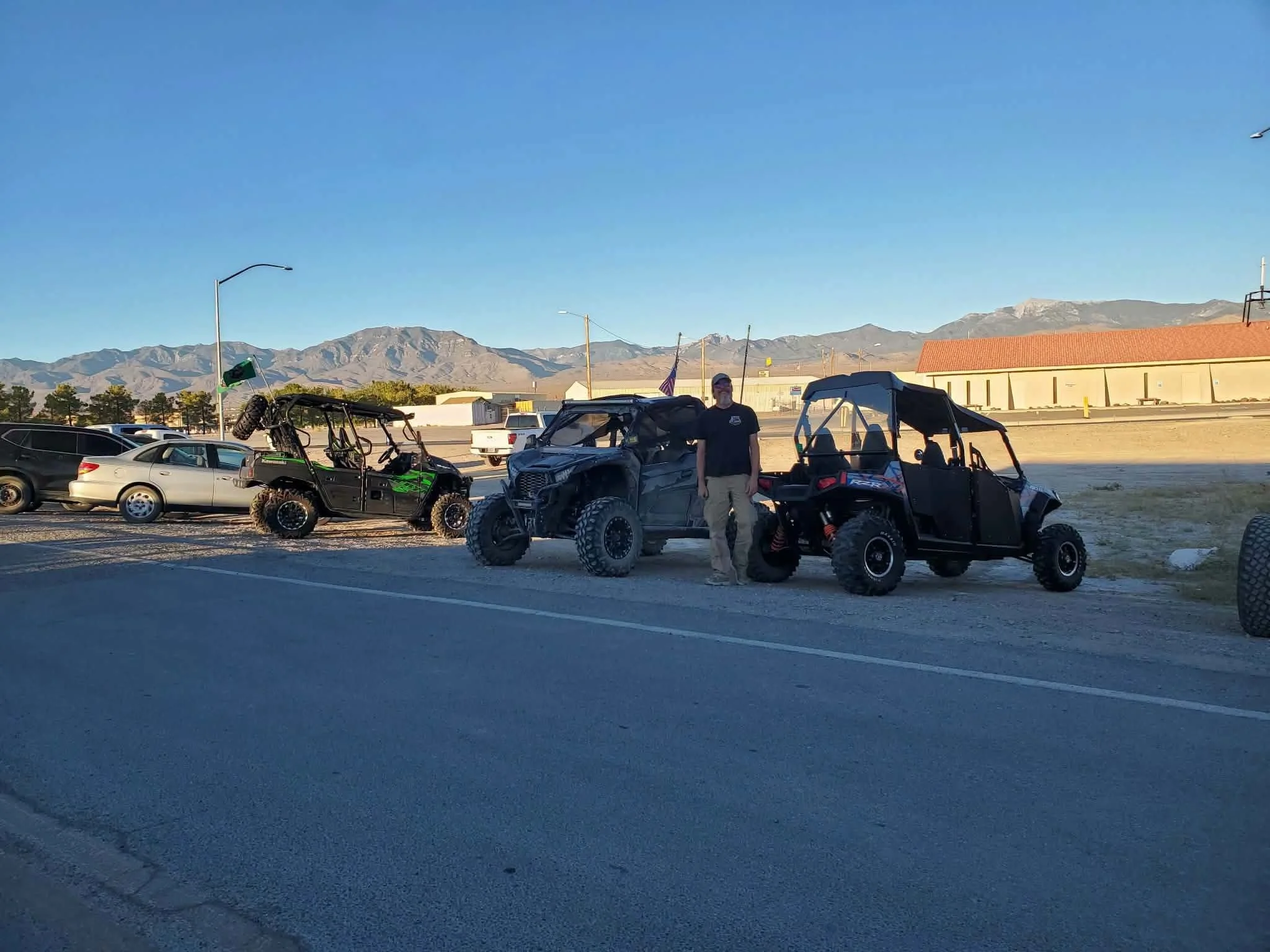Nye County SxS member standing between three off-road UTVs with mountains in the background at the September 2026 monthly meet