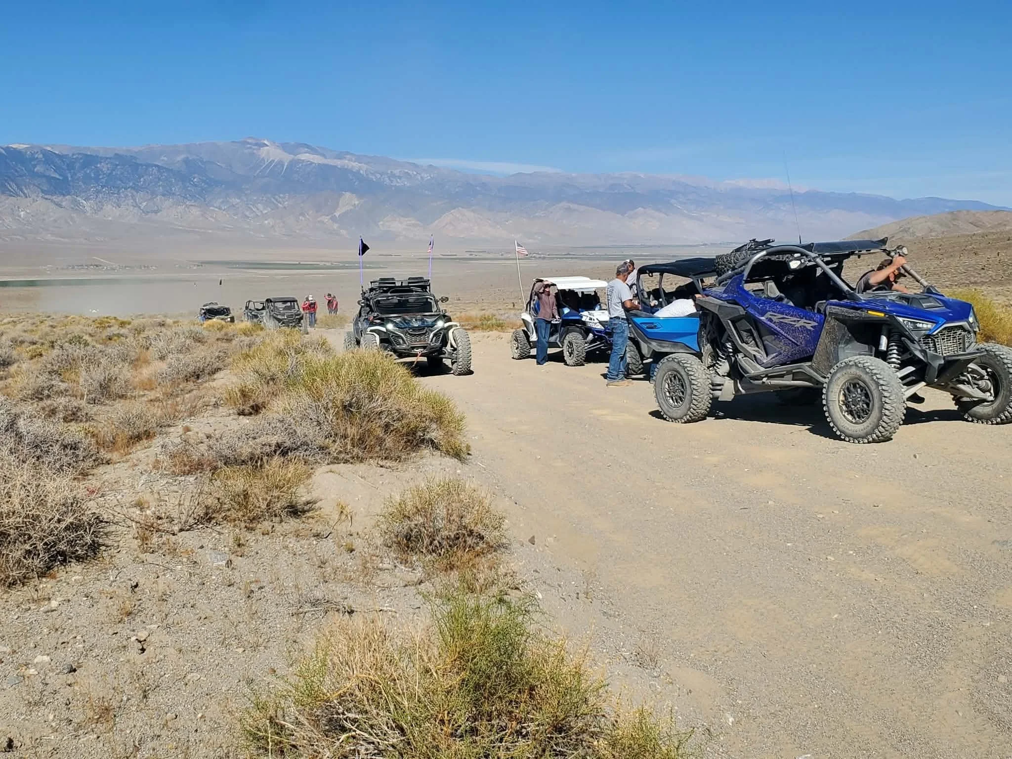 Riders and off-road UTVs parked along the desert trail during the 2026 Dyer - Fish Lake Poker Run