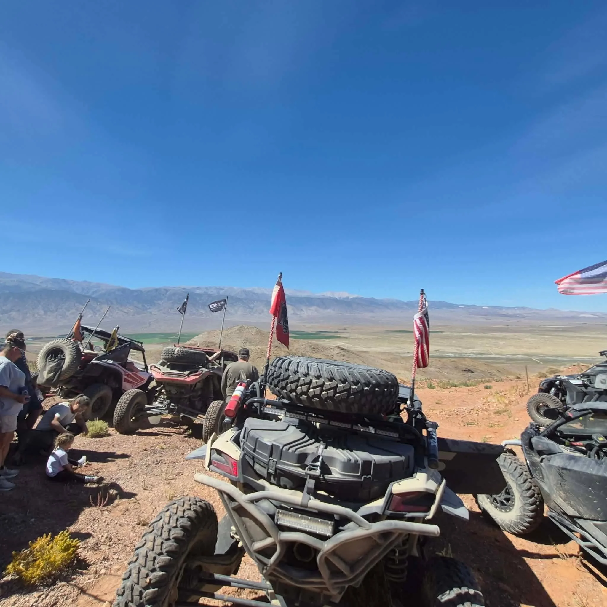 Flags and off-road vehicles parked on a ridge with mountains in the background during the 2026 Dyer - Fish Lake Poker Run