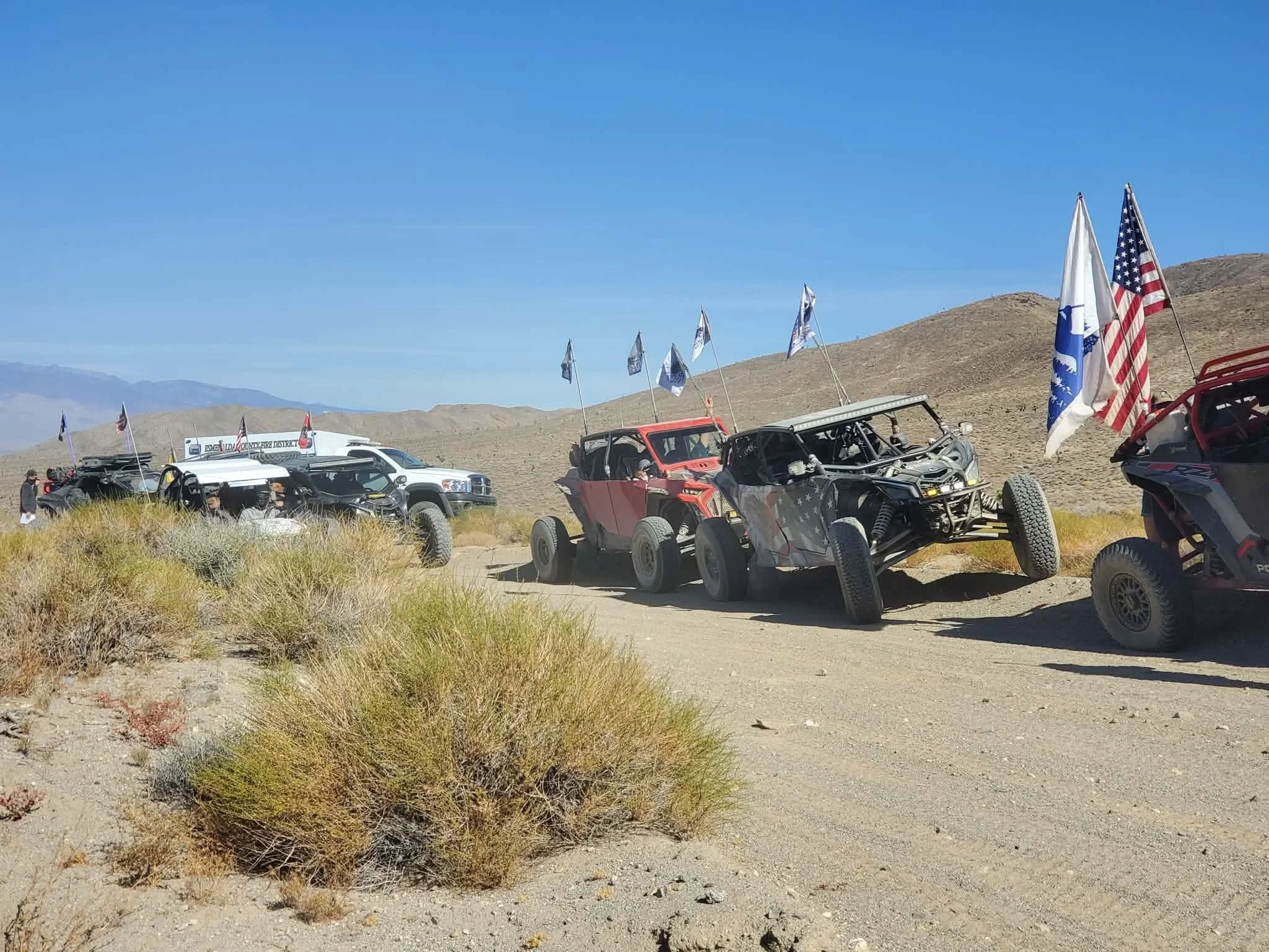 Off-road UTVs with flags parked on the hillside trail during the 2026 Dyer - Fish Lake Poker Run