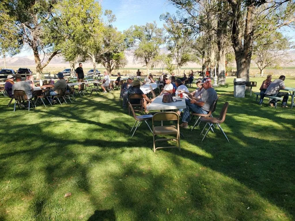 Wide view of riders gathered under shade trees at the campground during the 2026 Dyer - Fish Lake Poker Run