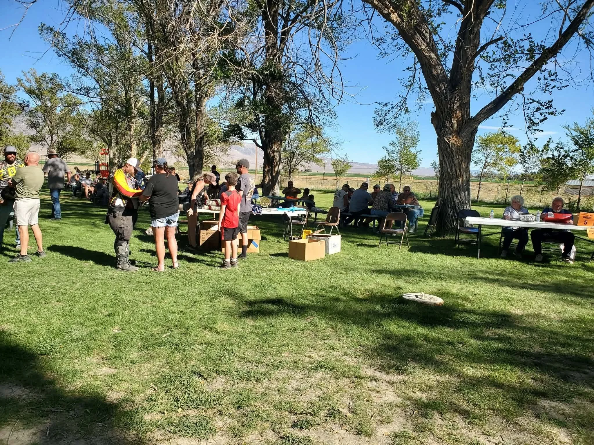 Riders gathered around picnic tables for a potluck meal during the 2026 Dyer - Fish Lake Poker Run