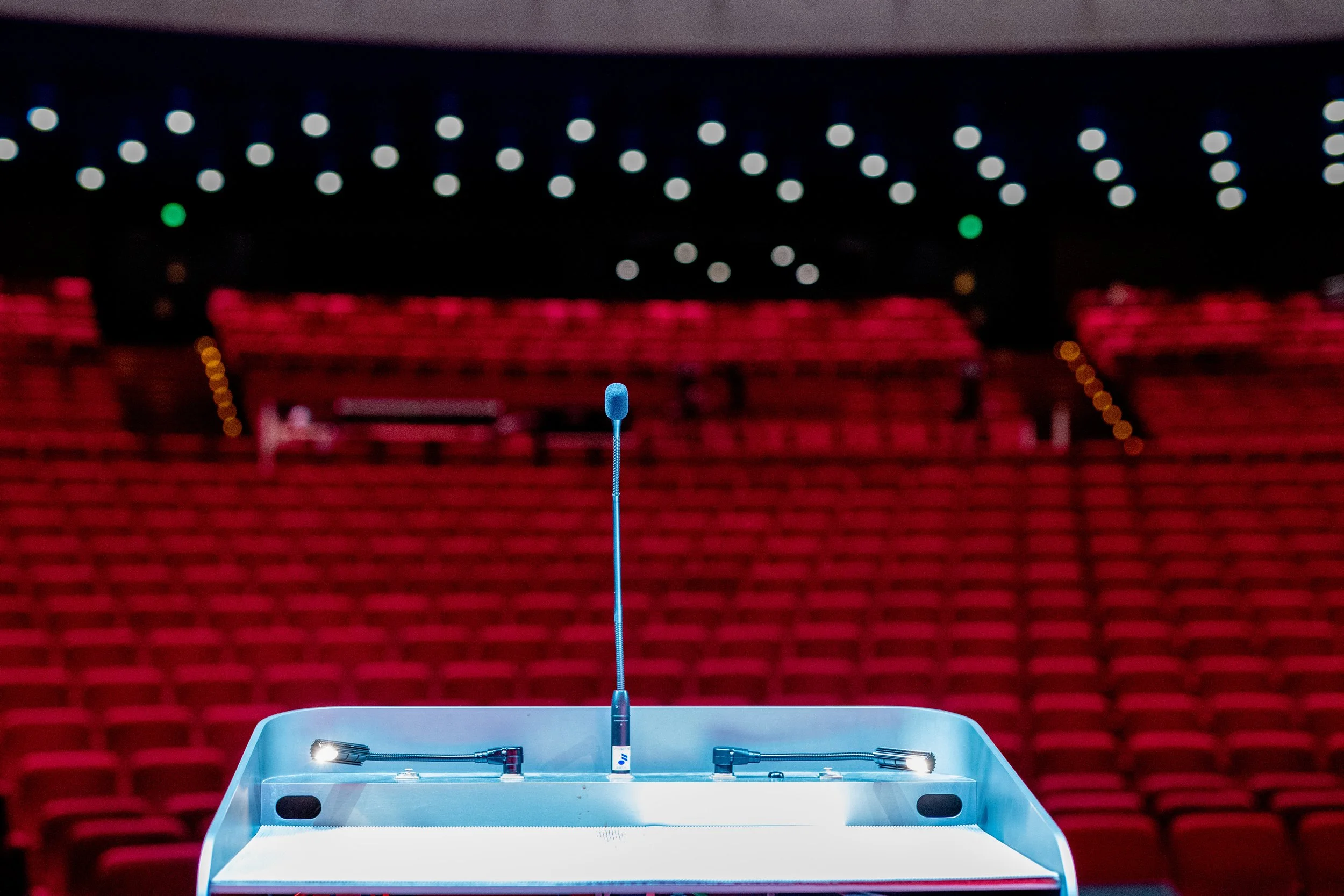 Concert hall with red seats and overhead ceiling lights. with microphone