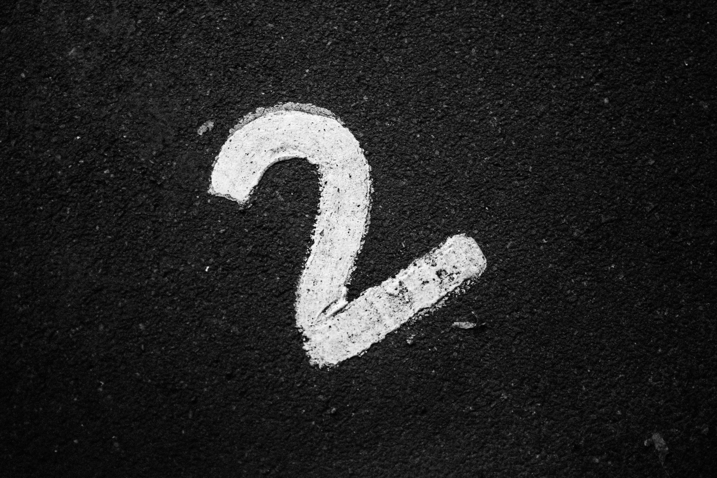 White number 2 painted on black asphalt surface