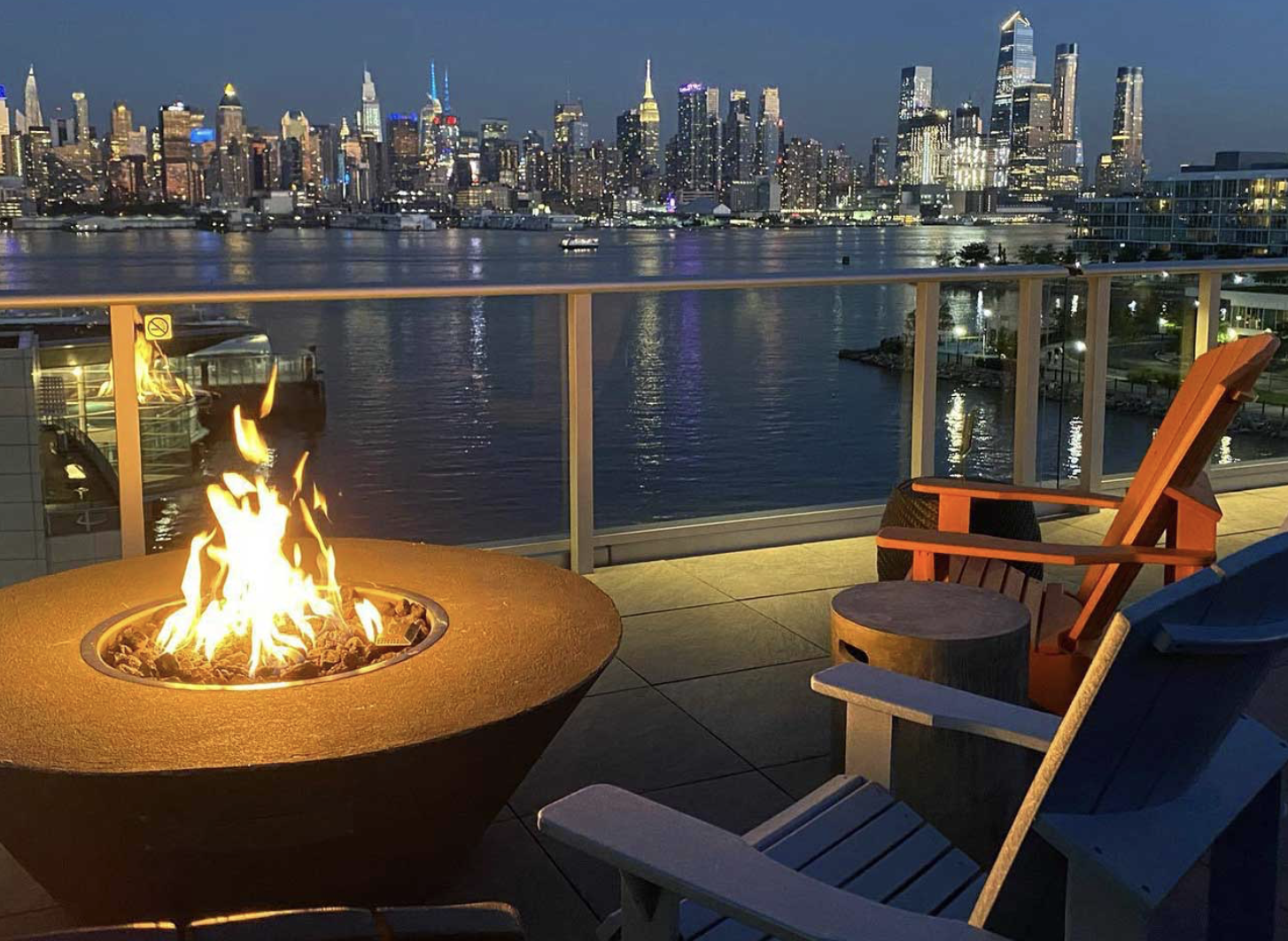 image of a fire pit on a rooftop bar overlooking the Hudson River and NYC skyline