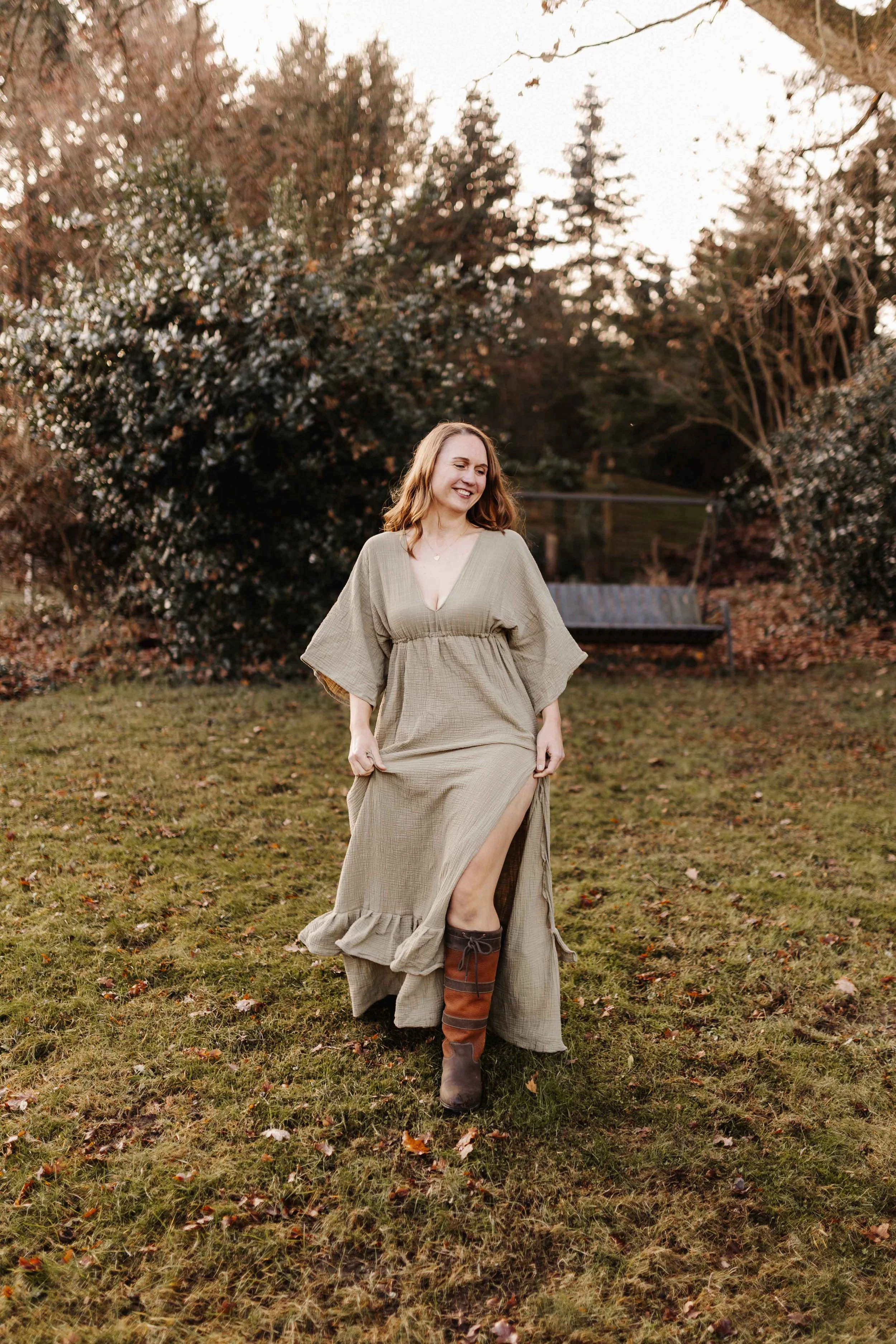 Frau im oliven Kleid mit Schlitz im Garten mit Stiefeln