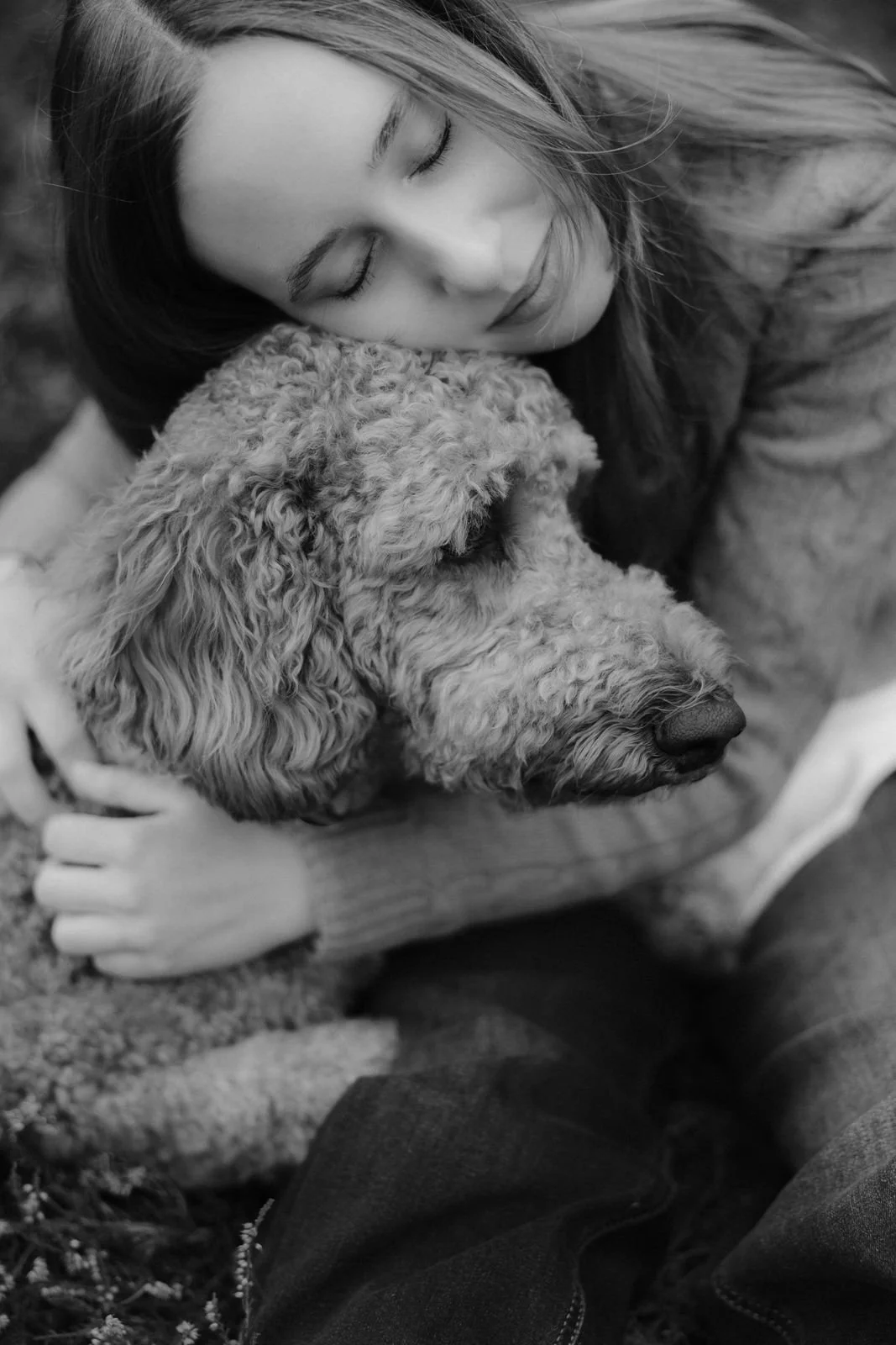 Schwarz-Weiß-Aufnahme einer Frau, die ihren Hund liebevoll umarmt und den Kopf an ihn schmiegt