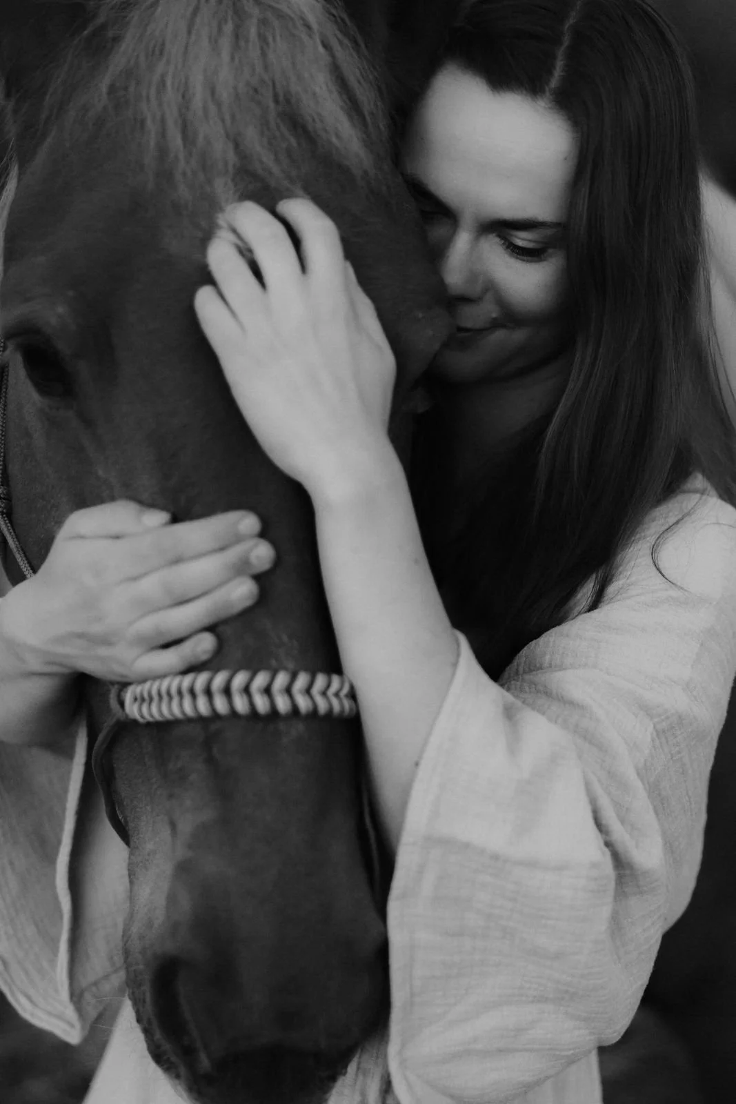 Junge Frau umarmt ihr Pferd innig und liebevoll, fotografiert in Schwarz-Weiß