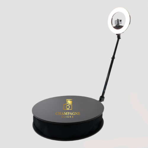 A ring light on a stand shining on a black display tray with a camera and the text "Champagne Clicks".