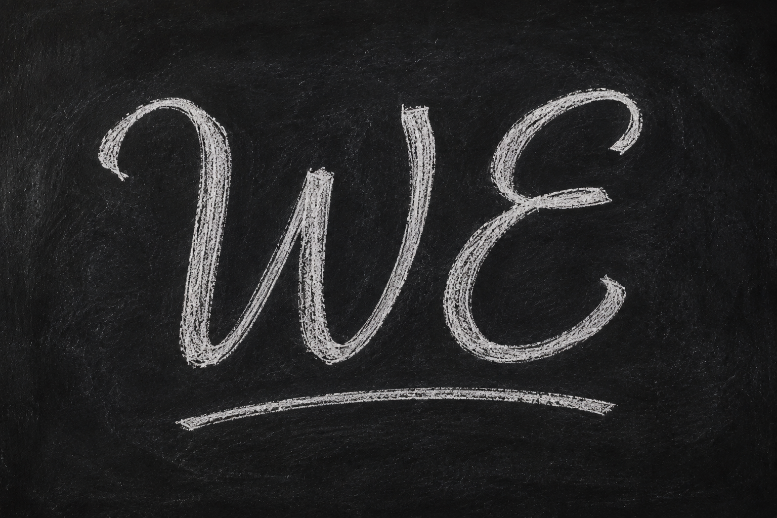 The word "WE" written in white chalk on a blackboard.
