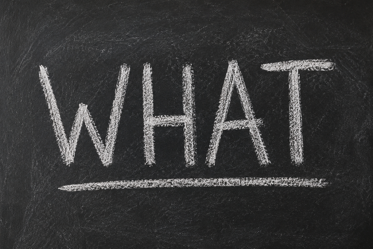 The word "WHAT" written in white chalk on a blackboard.