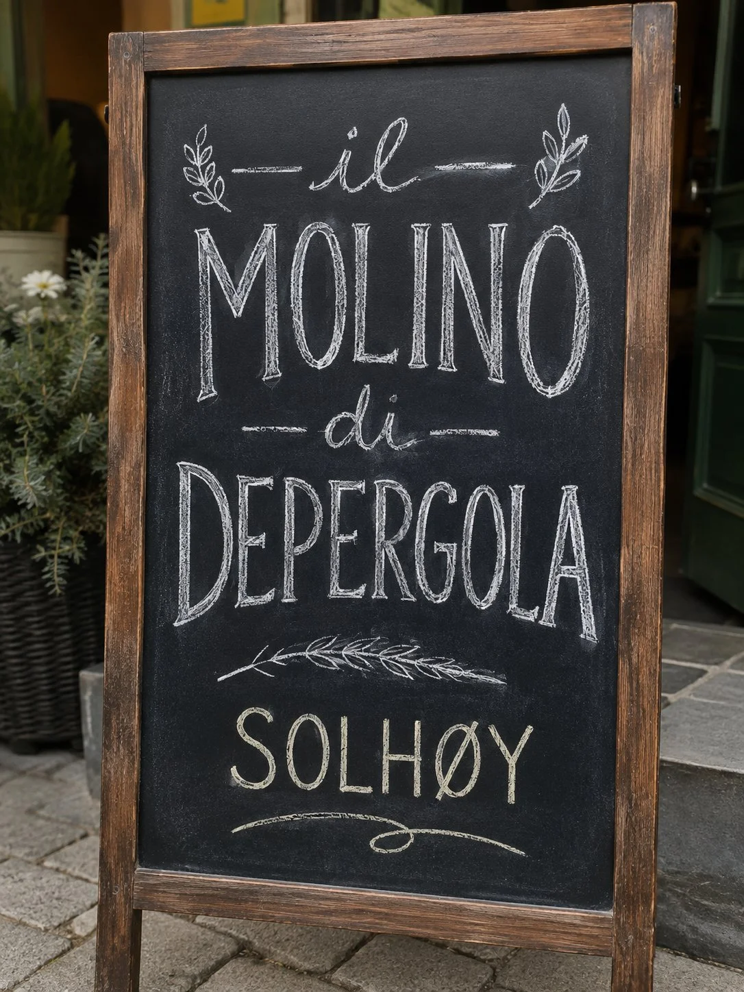 Weathered chalkboard sign reading "Il Molino di Depergola Solhøy," decorated with hand-drawn leaves.