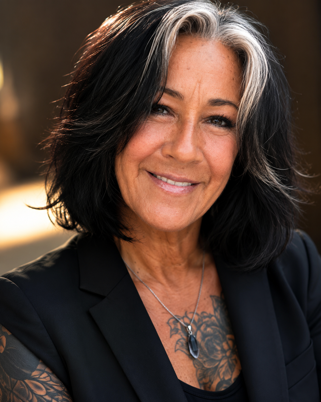 Close-up portrait of a middle-aged woman with black and gray hair smiling outdoors
