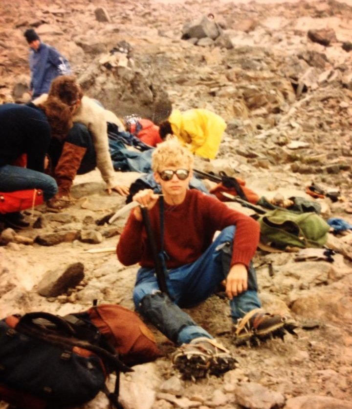 Young Samuel Nigro resting on rocky terrain during a Mount Rainier ascent in Washington State.